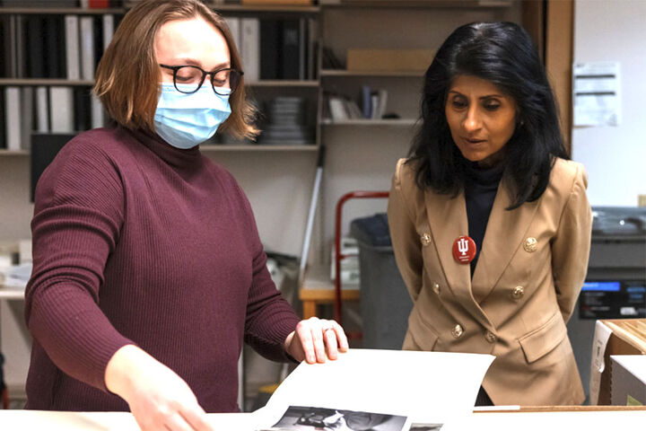 Chancellor Latha Ramchand studies a book with a female.